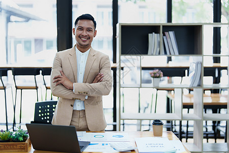 一位男性企业主的肖像 他在工作中使用计算机和财务预算文件成功地投资了他的企业时 脸上挂着快乐的笑脸人士律师双臂衬衫电脑面试套装幸图片