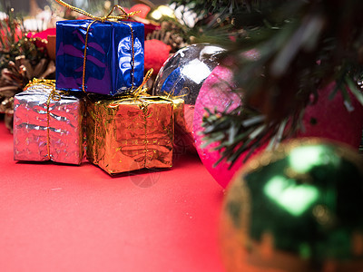 圣诞礼物盒 以不同颜色包裹在圣诞节树下红色背景的圣诞树上假期问候语庆典礼物丝带季节风格绿色木板卡片图片