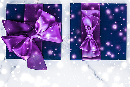 紫色礼物盒冬季假日礼物盒 带有紫丝弓 大理石背景上的雪亮如圣诞节和新年赠送给豪华美容品牌 平板设计娘娘腔雪花礼物丝绸问候销售推广丝带假期辉背景