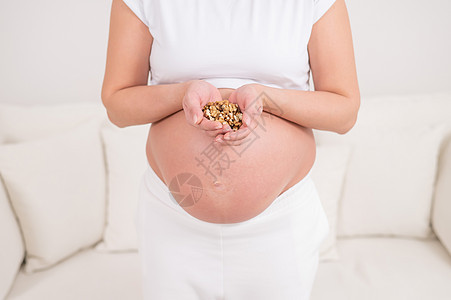 孕妇拿着一小撮核桃早餐保健饮食食物家庭身体脂肪女性活力母性图片