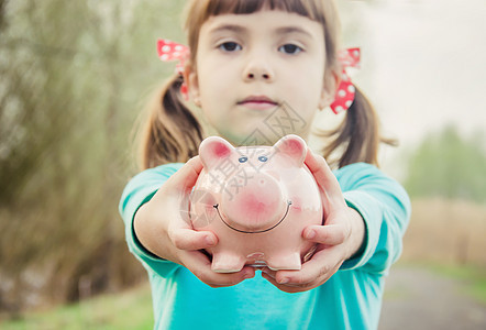 小猪银行在孩子的手里 储蓄 有选择性的专注商业家庭孩子们财富女儿男人微笑婴儿金融房子图片