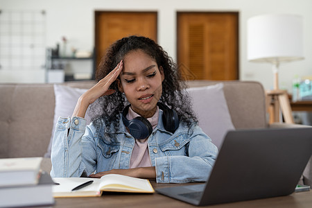 筋疲力尽的非洲裔美国女商务人士在办公室头痛 无聊的非洲年轻女孩厌倦了学习 坐在家里看着笔记本电脑 冷漠的黑人女大学生感到沮丧图片