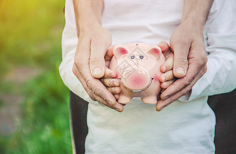 子女和父母手中握着一家小猪银行 他们正在等待金融存钱罐父亲孩子们木板银行业腮腺炎盒子财富店铺图片