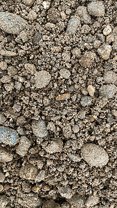 泥土的灰色细石质 小黑色背景 由路石制成图片