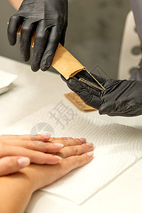 修甲师傅取出指甲工具 从美甲沙龙的克拉夫特信封里拿出来包装顾客手指美容乐器护理手套消毒成人身体图片