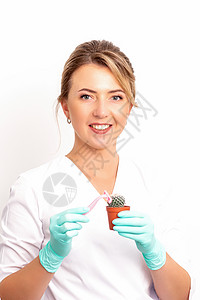一位微笑的女性美容师手里握着剃刀的小绿仙人掌 摘掉头发的概念治疗程序美容脱毛护理医疗手指激光卫生身体图片