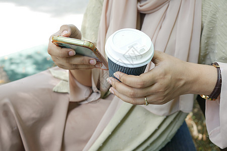 手持智能电话和纸咖啡杯的妇女杯子技术互联网屏幕手机商业背景图片