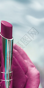 紫色口红和玫瑰花在液体背景上 防水玻璃化妆品和唇膏化妆品产品 用于豪华美容品牌假日设计季节管子展示推广礼物光泽度魅力假期销售奢华图片