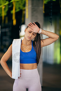健康的年轻女子在健身房接受培训后放松毛巾运动员福利重量减肥瓶子训练口渴身体休息图片