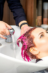 洗涤染过的女性头发 一位年轻的白人妇女正在美容院洗头 专业美发师正在洗掉顾客头发上的粉红色颜料染色职业工作理发师龙头发型女孩美容图片