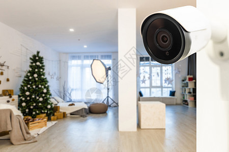 在舒适公寓的白墙上拍摄现代无线监视摄像头 近距离瞄准物体居住监视器手表安全凸轮男人隐私视频沙发眼睛图片