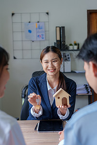 一名房地产代理商的肖像 在签署合同后为一对夫妇制作带有钥匙的房屋模型金融夫妻预算投资办公室女士营销计算器帐户会计图片