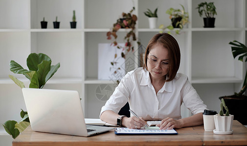 严肃专注的亚洲 40 多岁女商务人士执行经理坐在办公桌前 在现代办公室的 PC 笔记本电脑上打字 商业在线技术概念便利商务手机中背景图片