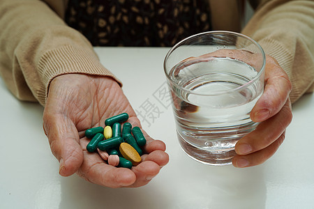 亚洲老年妇女在玻璃杯中拿着药丸 强烈的健康医学理念病人剂量帮助药片医生食物治愈胶囊诊所医院图片