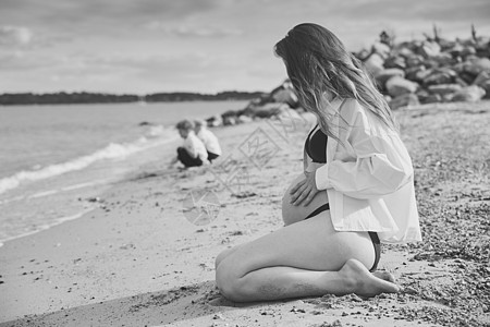 美丽的孕妇和儿子一起在海边放松的美丽孕妇图片