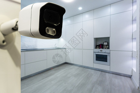 在舒适公寓的白墙上拍摄现代无线监视摄像头 近距离瞄准物体警报手表技术相机间谍眼镜长椅眼睛记录隐私图片