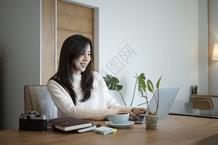 在毛衣冲浪的互联网上微笑的女人 家里有笔记本电脑图片