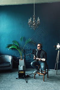 音乐工作室男歌手坐在凳子上 戴着耳机 吉他在家庭录音室录制曲目人声流行音乐音乐家幸福麦克风嗓音生产演员记录歌曲背景