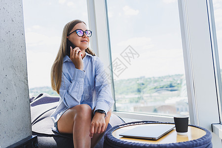 美丽的年轻女商务人士在智能手机上聊天 为公司开展新的生产力项目 在合作中心度过空闲时间 欣赏窗外美景办公室屏幕细胞互联网黑发衬衫图片