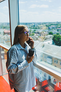 美丽的年轻女商务人士在智能手机上聊天 为公司开展新的生产力项目 在合作中心度过空闲时间 欣赏窗外美景商业经理人士细胞眼镜博主互联图片