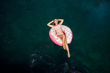 穿泳衣的年轻女子在海中的充气环上游泳 暑假概念女孩微笑棕褐色假期幸福水池太阳横幅乐趣游泳衣图片