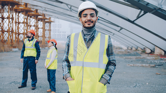 阿拉伯男子身着安全头盔和防弹背心的肖像 站在建筑工地图片