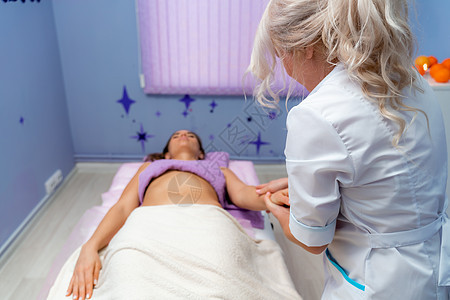 按摩女人的金发按摩治疗师 在水疗中心接受按摩的女人理疗整骨病人成人疼痛疗法身体药品诊所服务图片