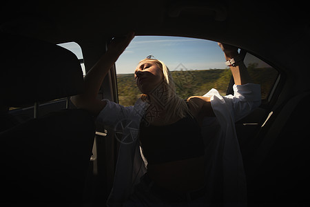 一位美丽的女孩骑着汽车快速地乘车 享受窗外的风声 工作休息和繁忙 宁静和自由情况旅行警告车辆朋友快乐姿势运输失败引擎图片