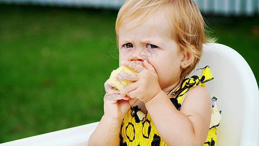 一岁漂亮的金发美女 在桌子上吃着苹果 上面放着花生土石的蘋果图片