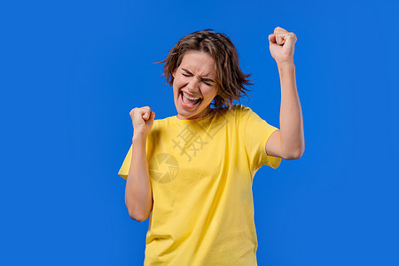 漂亮女人表现出胜利是胜利的姿态 她取得了成果 目标 蓝色背景的女孩高兴 快乐 惊讶兴奋快乐的女士 头奖概念图片