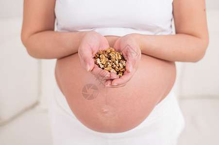 孕妇拿着一小撮核桃母性腹部婴儿家庭小吃肚子饮食早餐坚果母亲图片