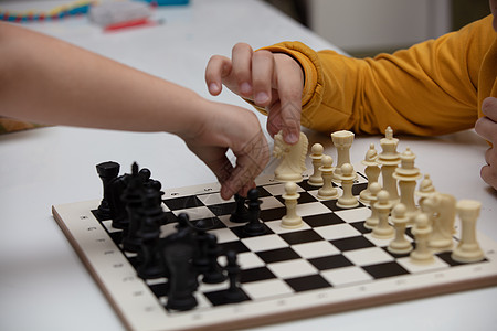 坐在一张桌子下棋 孩子全神贯注于游戏 思考着下一步该往哪里走 早期发展 儿童家庭教育游戏战略学习玩家爱好木板闲暇童年比赛运动数字图片