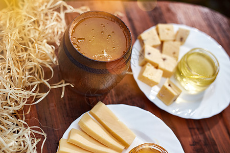 一罐甜蜂蜜 配奶酪和玫瑰 新鲜面包 明亮的光线 漂亮的装饰创意照片 放在花园木桌上的桶里 早餐时放着鲜花 美味的食物生态细胞摄影图片