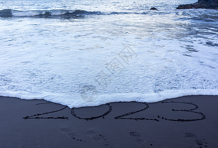 写在黑沙沙滩上的2023年符号数字旅游日历假期海浪情调新年异国海滩旅行背景图片