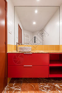 明亮的白色和黄色浴室中红色橱柜上的头顶白色水槽 墙上的白色和黄色瓷砖和瓷器棕色地砖 巨大的浴室壁镜 棕色浴室门风俗极简房间镜子装图片