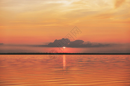 海中日落或日出 自然景观背景 红橙色云在天空中飞向阳光照亮水面 夜晚或早晨看到微笑和闪烁的太阳图片