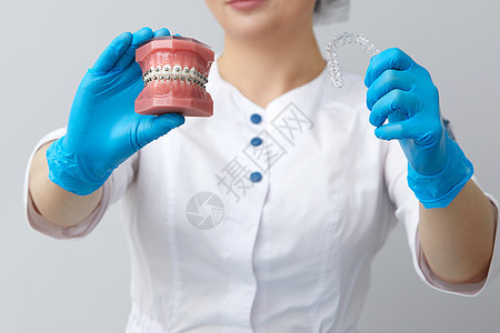 矫形医生展示人类下巴的模型 配有铁丝牙套和导线师解释差异技术矫正办公室塑料牙齿陶瓷制品治疗支撑药品图片