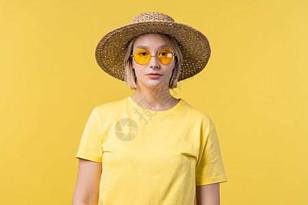 年轻漂亮的金发美女的肖像 在夏季黄色工作室的背景 自信的阳光明媚的衣服 有墨镜和草帽人士女性快乐情感女孩女士头发商务喜悦微笑图片