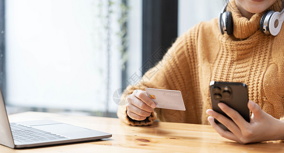 迷人的亚洲女性坐在她的办公桌前 拿着智能手机和信用卡 特写图像 网上支付 信用卡支付 手机银行 网上购物 无现金社会女孩技术商业图片