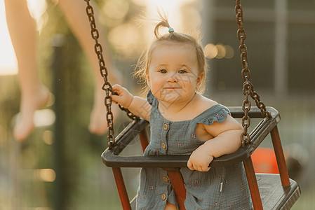 一个快乐的幼儿女婴 穿着洋装 在暖暑夜秋千喜悦童年微笑孩子孩子们幸福婴儿惊愕情感公园图片