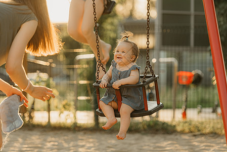 一个快乐的幼儿女婴 穿着洋装 在暖暑夜秋千喜悦童年女性操场婴儿惊愕孩子公园微笑女孩图片