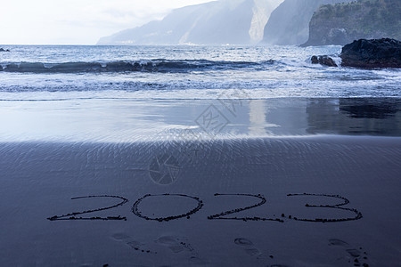 写在黑沙沙滩上的2023年符号旅游海滩幸福海洋假期日历新年异国海浪情调图片