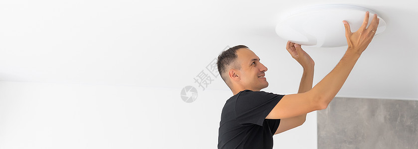 在室内伸展天花板修理灯的工人安装螺丝刀拉伸男性聚光灯建筑修理工男人维修工作图片