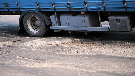 道路覆盖率极差 许多坑 弯曲沥青 一辆大卡车破旧地缓慢通过一段路段 公路需要修复图片