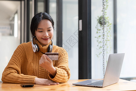 迷人的亚洲女性坐在她的办公桌前 拿着智能手机和信用卡 特写图像 网上支付 信用卡支付 手机银行 网上购物 无现金社会电话金融商业图片