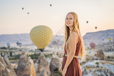 在土耳其卡帕多细亚看热气球的女游客 土耳其概念中的快乐旅行 山顶上的女人享受美妙的景色旅游空气日出女孩岩石男人地质学女士地标日落图片