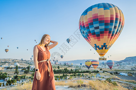 在土耳其卡帕多细亚看热气球的女游客 土耳其概念中的快乐旅行 山顶上的女人享受美妙的景色公园日出旅游日落夫妻蓝色航班女士天空悬崖图片