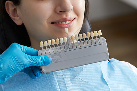 牙医为病人选择牙釉质的颜色 牙医将牙釉质标本应用于白人女性牙齿假牙微笑工具女士医生矫正样本成人诊所阴影图片