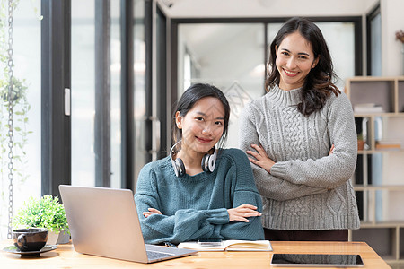 两位年轻的亚裔女性在工作上表现出愉快的成功表现 在现代办公室里带着笔记本电脑笑得开心商务胜利快乐职员手势团队手臂庆典讨论会议图片