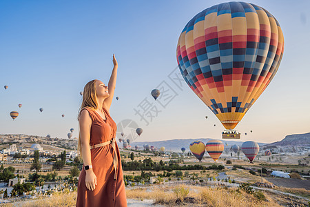 在土耳其卡帕多细亚看热气球的女游客 土耳其概念中的快乐旅行 山顶上的女人享受美妙的景色悬崖女士公园空气夫妻岩石假期石头自由女孩图片